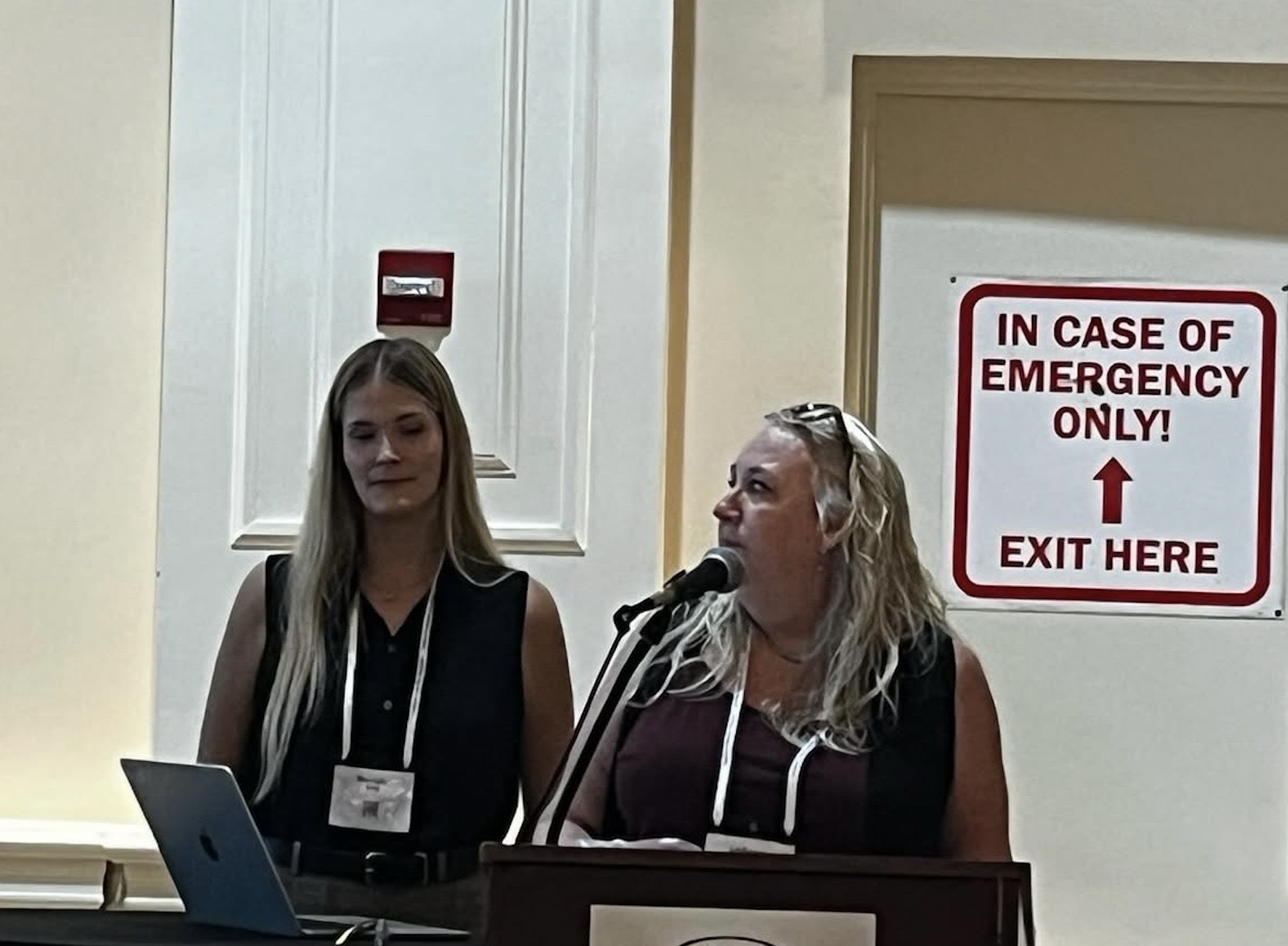 Two women standing at a podium. 